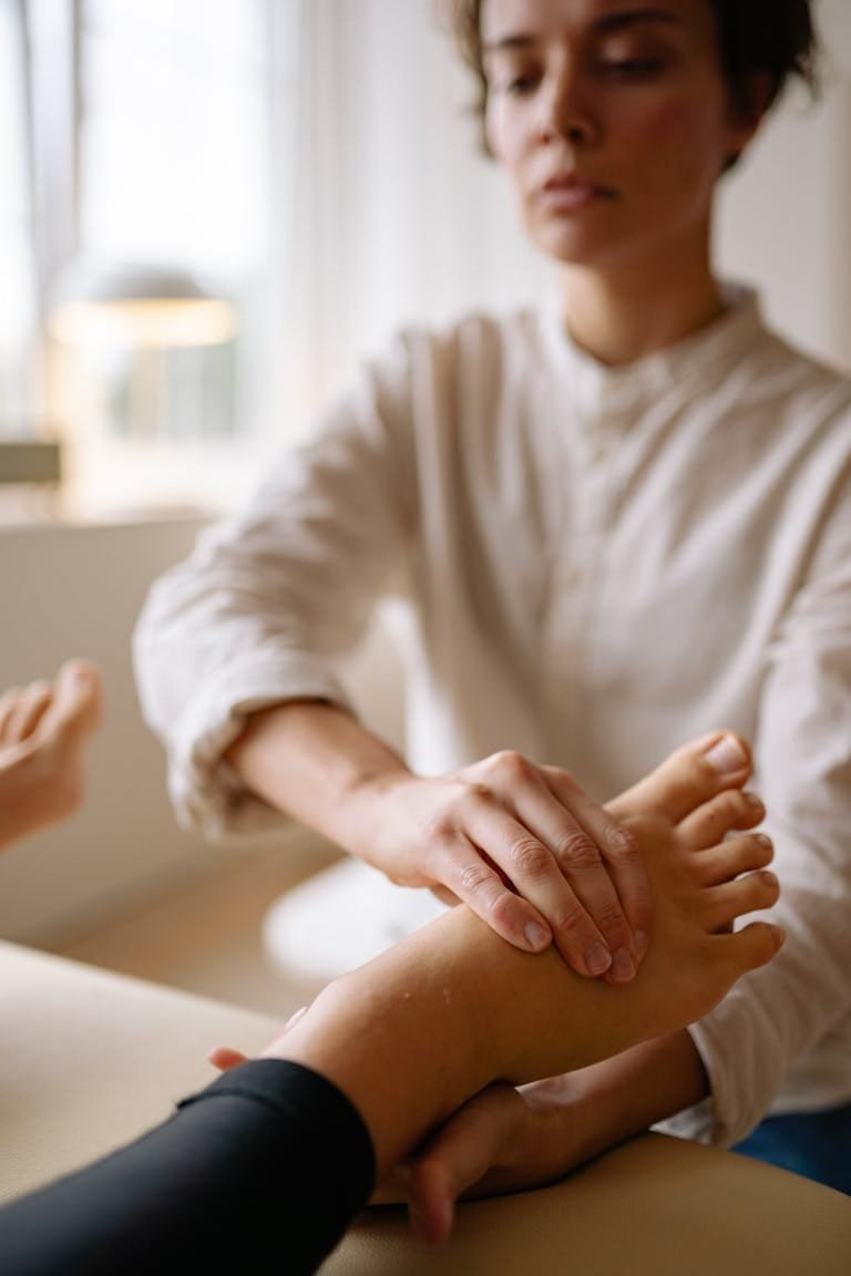 A therapist performing a foot massage on a client in a serene indoor setting.