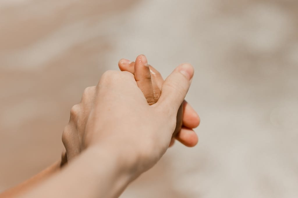 Close-up of adults holding child's hand on a beach in Aracati, Brazil.