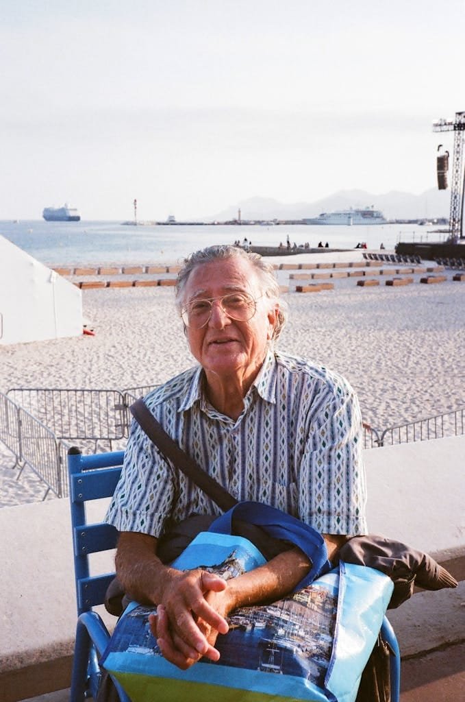 Senior adult enjoying a sunny day on a beach with a serene sea backdrop.