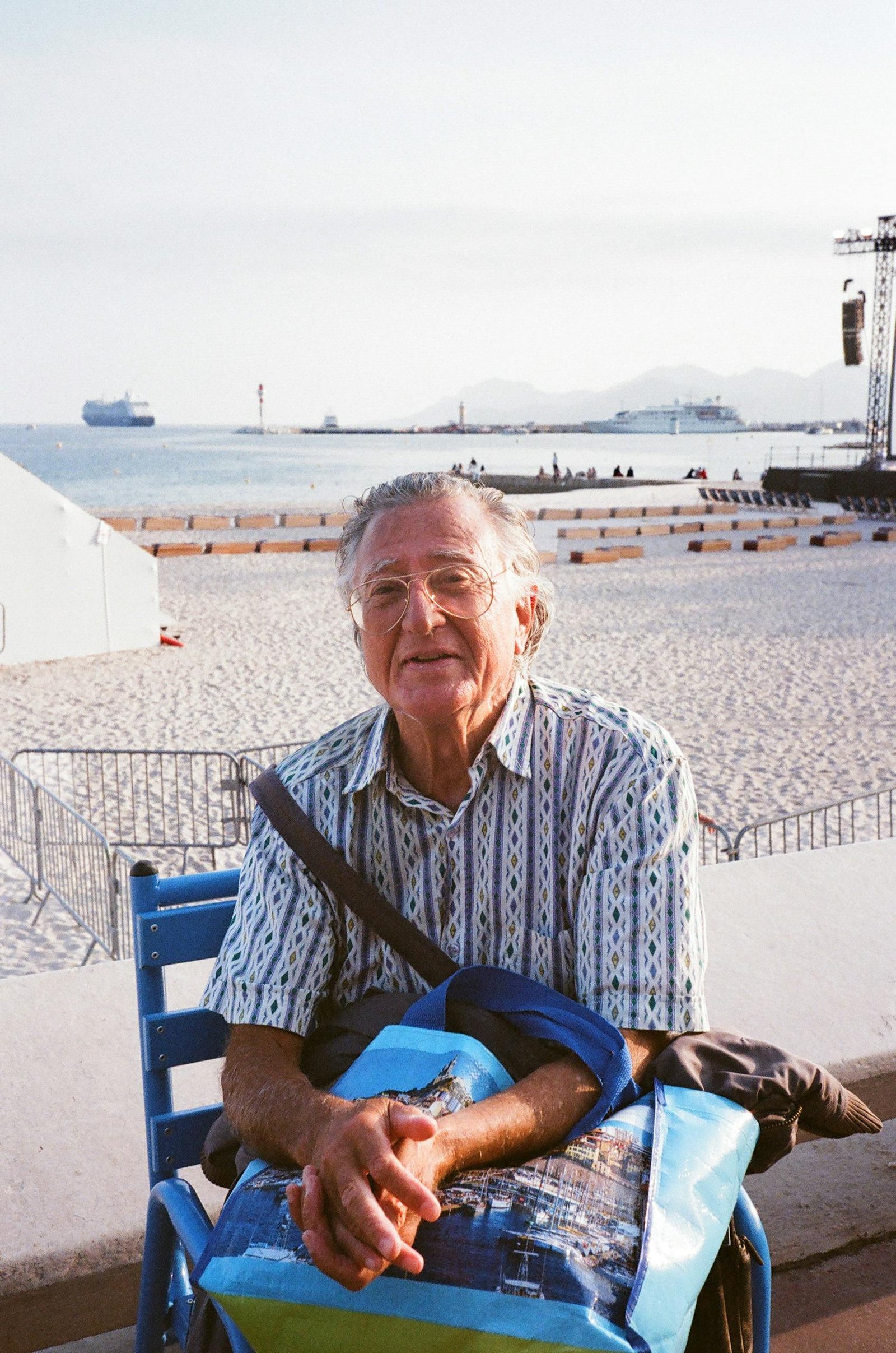 Senior adult enjoying a sunny day on a beach with a serene sea backdrop.