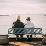 Senior couple enjoys a peaceful moment on a bench overlooking the sea.