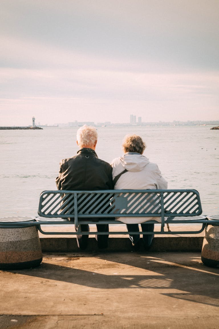 Senior couple enjoys a peaceful moment on a bench overlooking the sea.