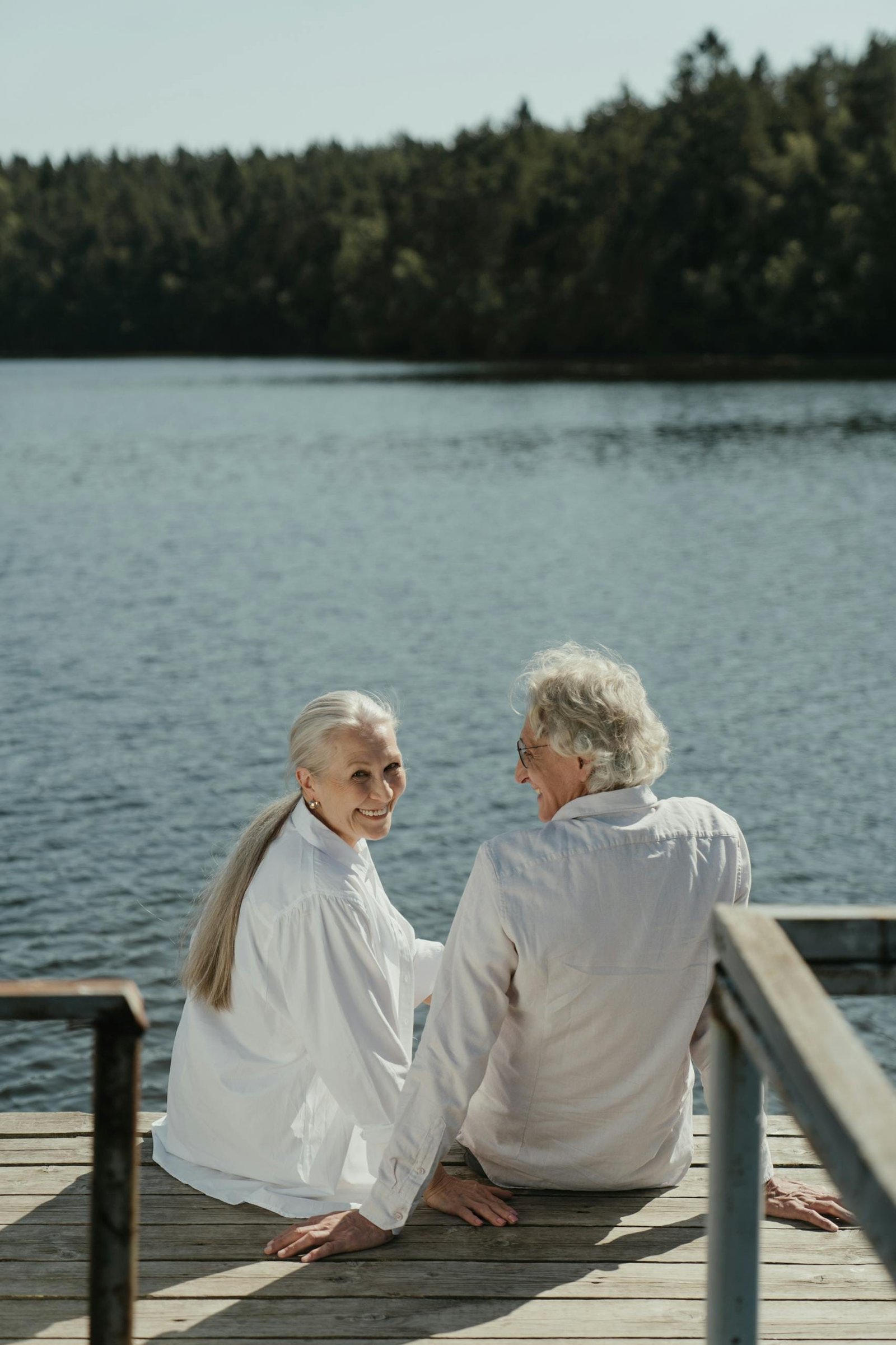 Serene lakeside moment with a senior couple enjoying time together on a wooden dock.